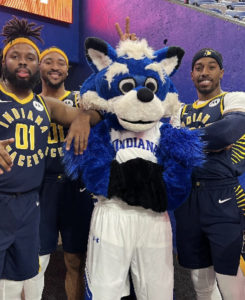 Three men in blue Pacers Power Pack basketball jerseys pose with Indiana State's mascot, Sycamore Sam.