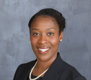 Bre'Anna Donaldson, a Black woman with short black hair, poses in a headshot. She wears a black blazer with a pearl necklace.